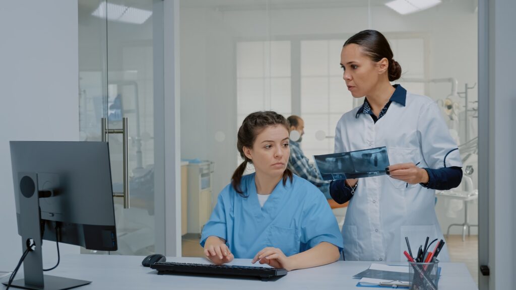 Team of nurse and stomatologist examining x ray and computer